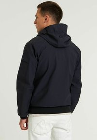 Chaqueta con capucha en color marino que presenta una textura suave, puños elásticos y un bolsillo con cremallera en la manga. Diseñada para la funcionalidad y la comodidad.