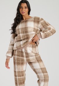 Braun und cremefarbenes karriertes Loungewear-Set aus weichem, flauschigem Material. Mit langen Ärmeln, lockerer Passform und elastischem Bund an der Hose.
