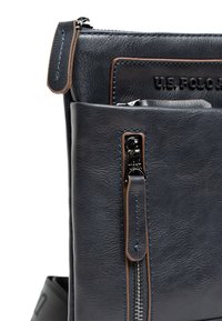 Borsa in pelle blu navy con superficie texturizzata, dotata di chiusura a zip superiore e tasca frontale con cuciture marroni e zip metallica.