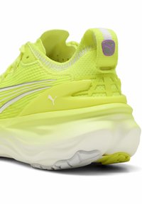 Baskets de course jaune fluo avec une tige texturée, des accents blancs et une semelle rembourrée. Présente un logo au niveau du talon et un design de contrefort de talon soutenant.