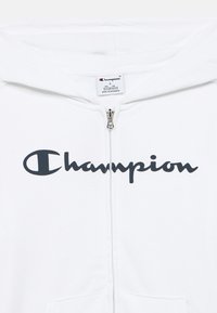 Λευκό φούτερ με φερμουάρ και μεγάλο μαύρο λογότυπο "Champion". Απαλό ύφασμα με κουκούλα, μπροστινές τσέπες και μεταλλική λεπτομέρεια φερμουάρ.