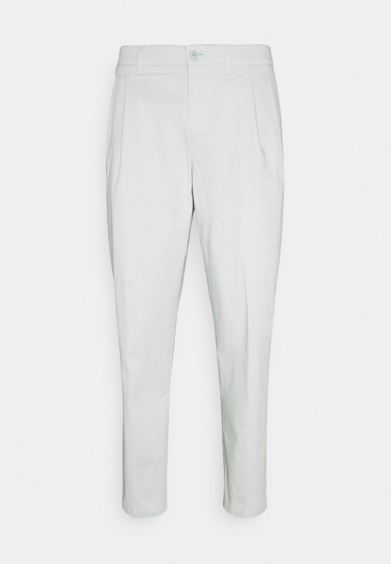 Weiße, zulaufende Hose aus leichtem Stoff, mit einer vorderen Bügelfalte, Knopfverschluss und Gürtelschlaufen. Glatte Textur ohne auffällige Muster.