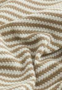 Gestrickter Stoff in abwechselnden beige- und weißen Streifen, mit einer weichen Textur und einem welligen Muster. Das Material wirkt warm und gemütlich.