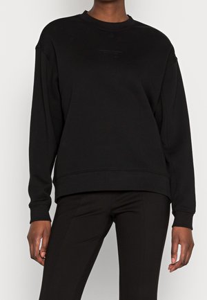 Sweat-shirt noir avec un col rond, des manches longues et une coupe décontractée. Le matériau semble doux avec un design minimaliste à l'avant.