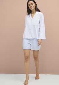 Set di pigiama a righe blu chiaro composto da una maglietta con bottoni a maniche lunghe e pantaloni corti abbinati, realizzato in un tessuto morbido con vestibilità comoda.
