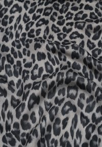 Tessuto con stampa leopardata caratterizzato da uno sfondo grigio con macchie nere, texture liscia e leggero riflesso, disposto in modo fluente.