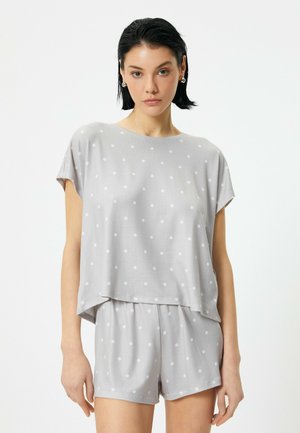 Grå pyjamas sæt med polkaprikker, der har en kortærmet bluse med en løs pasform og matchende shorts. Lavet af blødt, komfortabelt stof.