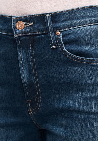 Tumesinised teksapüksid, millel on sile tekstuur, vasknupu sulgemine, peened õmblused ja klassikaline viie-taskumise disain.