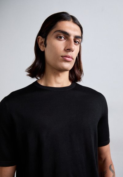 Schwarzes T-Shirt mit kurzen Ärmeln, aus einem weichen, leichten Stoff gefertigt, mit klassischem Rundhalsausschnitt und taillierter Silhouette.