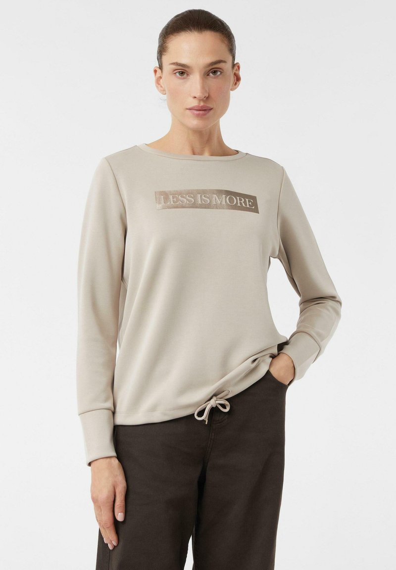 Jasno beżowy sweatshirt z długim rękawem, z błyszczącym napisem "LESS IS MORE" z przodu oraz detalem w postaci sznureczka u dołu.