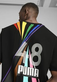 Maglietta nera con strisce diagonali colorate in arancione, giallo, verde, blu e rosa. Presenta i numeri bianchi in bold "48" e il logo "PUMA".