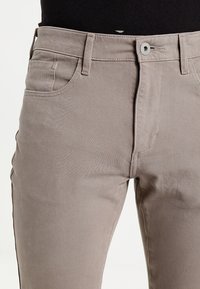 Lichtgrijze denim broeken met een slim fit, uitgerust met een knoopsluiting, vijf zakken en subtiele stikdetails langs de naden.