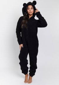 Mono de forro polar negro con capucha que presenta orejas de oso, cierre completo con cremallera y puños acanalados. Textura suave con ajuste relajado y piernas ajustadas.