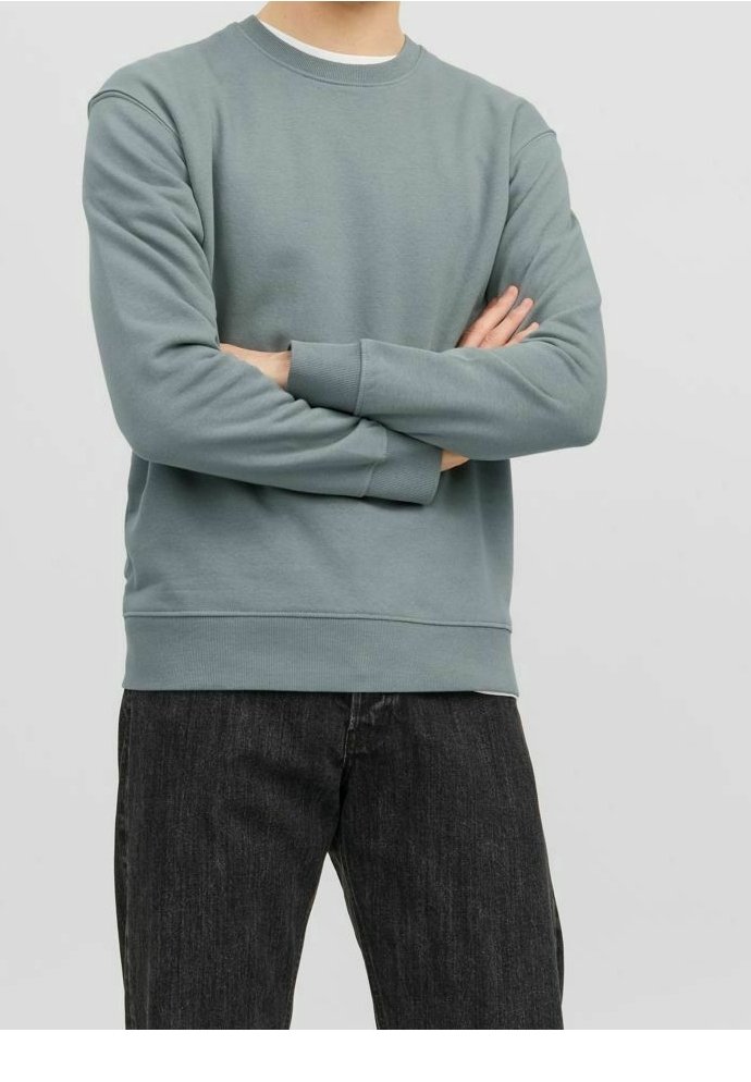 Jasnoniebieska bluza z miękkiego materiału, z okrągłym dekoltem i ściągaczami przy mankietach. Połączona z ciemnymi jeansami.