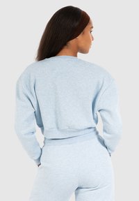 Felpa azzurra chiara con una vestibilità comoda, polsini e orlo a costine. Realizzata in tessuto morbido, presenta un collo a giro e una texture minimale.