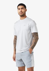 Jasnoszary T-shirt sportowy z krótkimi rękawami i dyskretnym logo na piersi, w połączeniu z jasnoszarymi szortami z bocznymi akcentami.