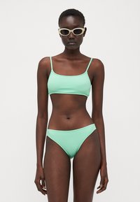 Mentazöld, textúrázott bikini, crop toppal és alacsonyan nyugvó alsó résszel, vékony pántokkal és sima felülettel.