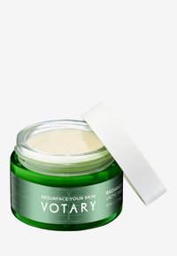 Grön glasburk med ett vitt lock, innehållande en ljus kräm. Etiketten säger "Återställ din hud" och "Mjölksyra." Volym: 50 ml.