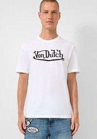 Witte katoenen t-shirt met een opvallend zwart "Von Dutch" logo in een gestileerd lettertype. Ronde hals en korte mouwen. Eenvoudig ontwerp.