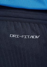 Pantaloni Corti Navy Dri-FIT ADV con tessuto testurizzato e logo riflettente argento. La parte superiore è blu chiaro con un motivo in rete.