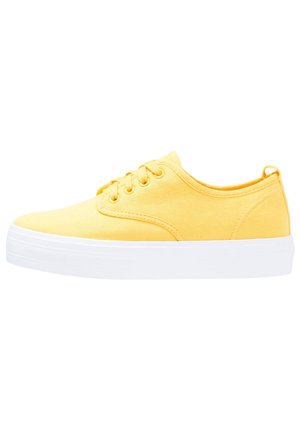 Gele canvas sneakers met witte rubberen zolen, vetersluiting, ronde neus en een gladde textuur. Minimalistische stijl zonder zichtbare patronen.