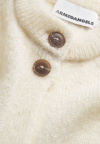 Maglione color crema con una consistenza morbida, dotato di un colletto e due bottoni marroni. Mostra un'etichetta ARMEDANGELS.