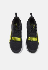 Pantofi sport negri cu partea superioară din plasă, având un logo „PUMA” proeminent de culoare galbenă și accente galbene, însoțiți de o talpă albă.