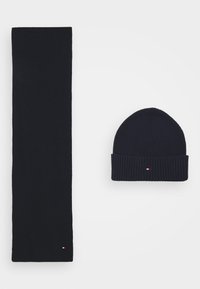 Navy Strickmütze und passender Schal, beide mit geripptem Textur. Die Mütze hat einen umgeschlagenen Saum und ein kleines Logodetail.