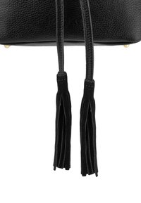 Sac en cuir noir avec une surface texturée, deux glands en suède et des accents en métal doré à la base. Présente un design épuré et minimaliste.