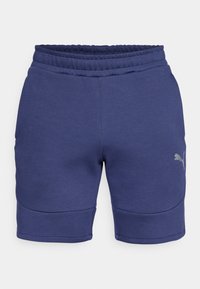 Marineblauwe shorts van zacht materiaal met een elastische tailleband, voorzien van gebogen naaddetails en een klein reflecterend logo aan de onderzijde.
