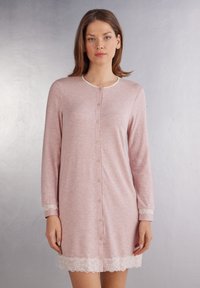 Ljusrosa nattlinne med långa ärmar, knäppning fram och spetsdetaljer vid nederkant och ärmslut. Tillverkat av mjukt, texturerat tyg.