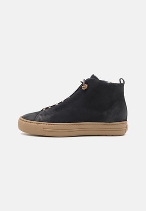 Bottes en daim bleu marine à la cheville avec une semelle en caoutchouc beige, présentant un design épuré et des détails de lacets décoratifs.