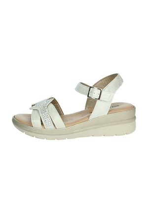 Sandalo in pelle bianca con una fascia testurizzata, dotato di un accento di strass. Cinturino alla caviglia regolabile e suola con zeppa contornata in beige.