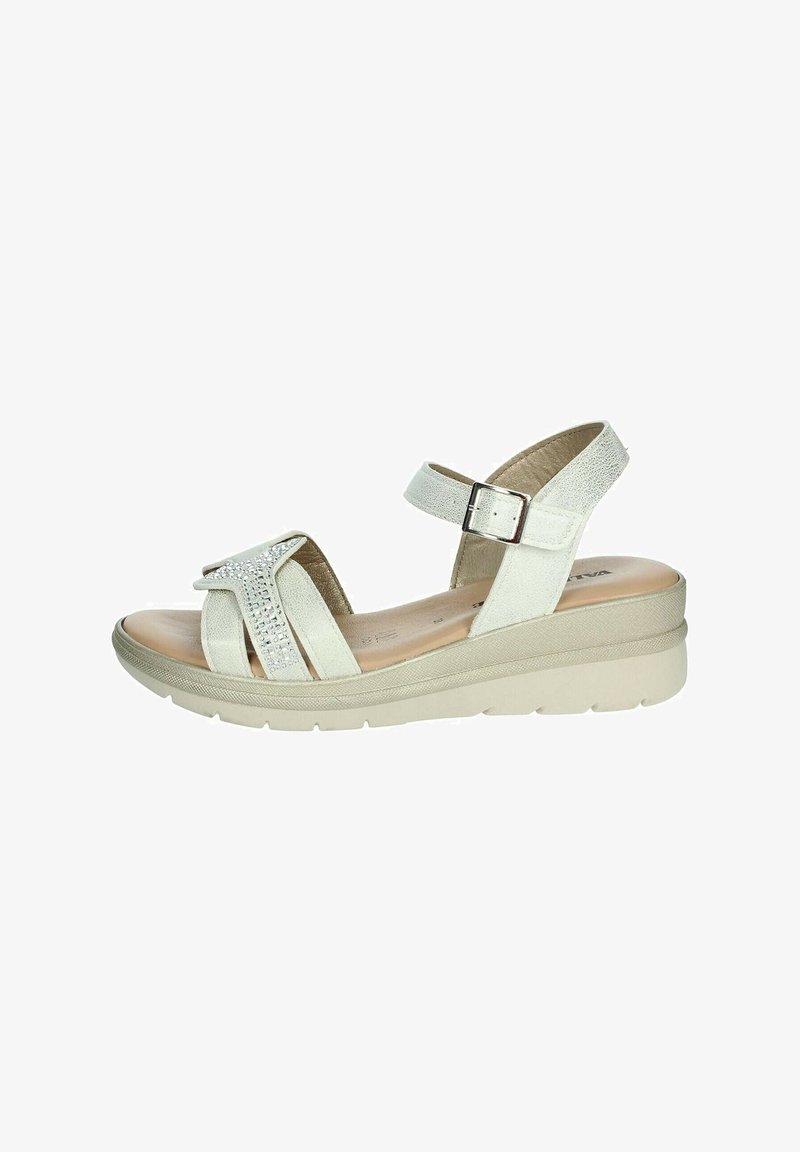 Sandalo in pelle bianca con una fascia testurizzata, dotato di un accento di strass. Cinturino alla caviglia regolabile e suola con zeppa contornata in beige.
