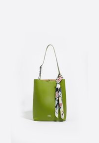 Bolso tote de cuero verde con una textura suave, presenta una bufanda de tela atada en el asa y una marca en relieve en la base.