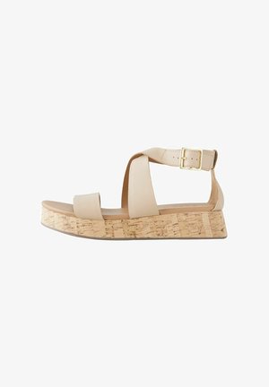Beige Plateau-Sandalen mit einem Kork-Blockabsatz, ausgestattet mit breiten Überkreuzriemen und einer Metall-Schnalle am Knöchelriemen.