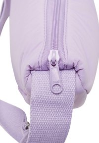 Borsa a zip di colore viola chiaro con una tracolla texturizzata. Presenta un cursore della zip liscio con l'etichetta "SBS" e un'esterno morbido e imbottito.