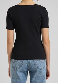 Sort ribbet kortærmet t-shirt med rund hals, tætsiddende pasform og blød tekstur, parret med lyseblå denim jeans.