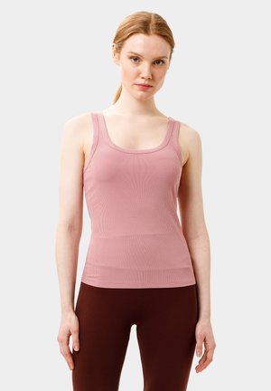 Lyserød ribbet tanktop med en rund halsudskæring og brede skulderstropper, båret med brune leggings; glat tekstur og tætsiddende design.