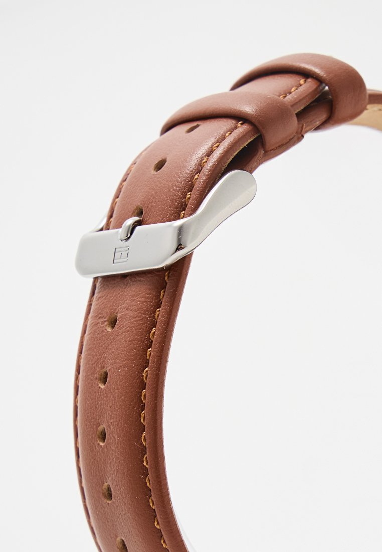 Brauner Lederuhrengurt mit Perforationen, versehen mit einer silbernen Metallschnalle und kontrastierenden Nähten entlang der Kanten.