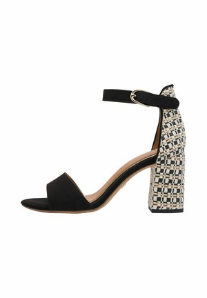 Black suede open-toe sandal with an ankle strap and a patterned woven block heel in black and white. Smooth texture, elegant design.