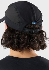 Black cap with mesh panels, adjustable strap at the back, featuring a small blue and yellow accent near the closure.