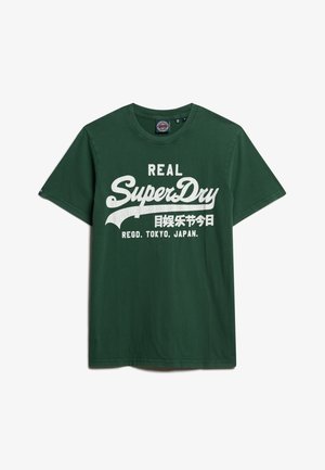 T-shirt verde in cotone con grande testo bianco che recita "REAL SuperDry" con caratteri giapponesi e "REGD. TOKYO, JAPAN."