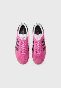 Pink suede athletic shoes with black stripes, white accents, and rubber soles; features round toe and contrasting laces.