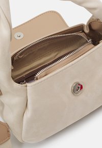 Beżowa torebka wykonana z faux leather o gładkiej fakturze, z wewnętrzną kieszenią na zamek oraz zapięciem na zatrzask z akcentami w srebrnym kolorze.