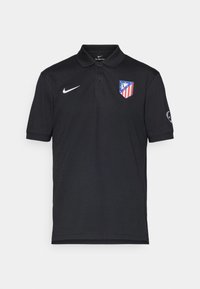 Sort poloshirt lavet af bomuld, med en tre-knaps placket, Nike-logo på brystet og Atlético Madrid-våbenskjold med røde og blå accenter.
