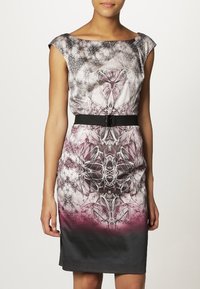 Figurbetontes Kleid aus bedrucktem Stoff mit floralem und geometrischem Muster, mit einem schwarzen Gürtelakzent in der Taille und einem Farbverlauf von Rosa zu Schwarz.