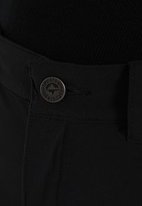 Černé kalhoty z hladké tkaniny, se zapínáním na knoflík s logem a nastavitelným stahovacím páskem v pase pro přizpůsobení střihu.