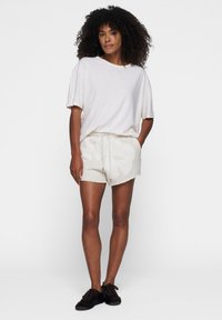 Hellgraues, übergroßes T-Shirt aus weicher Stoff, kombiniert mit cremefarbenen Shorts mit dezentem Blumenmuster und Kordelzug.