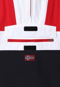 Rood, wit en marineblauw windjack met een ritszak, klittenbandaccenten en een geborduurde Noorse vlag. Getextureerde stof.
